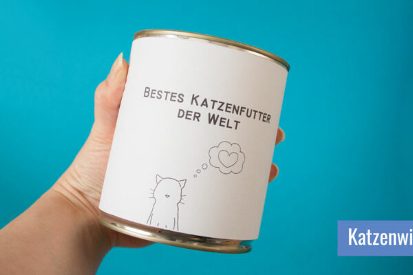 Hand hält eine große Futterdose, die mit "Bestes Katzenfutter der Welt" beschriftet ist